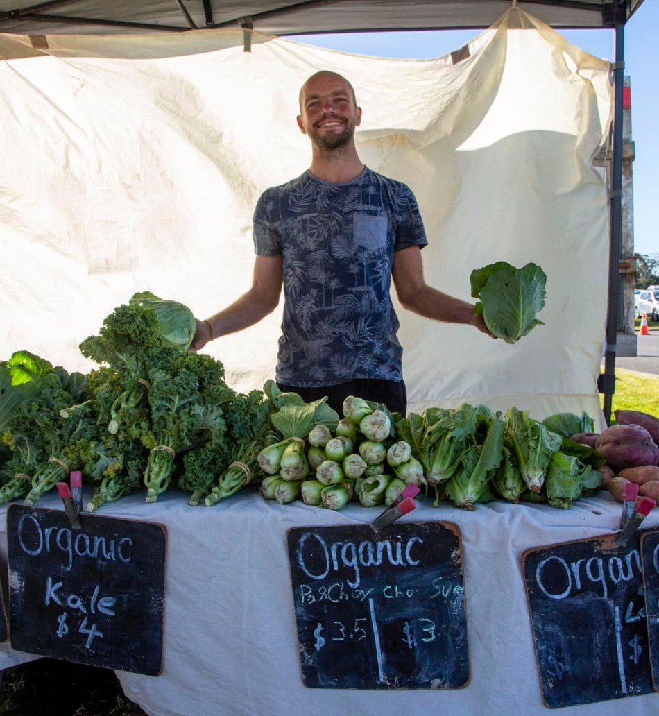 Markus at a market stall with organic kale and pak choy